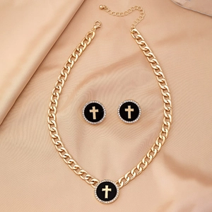 Detail view of gold cross jewelry set with black enamel and zircons on satin fabric