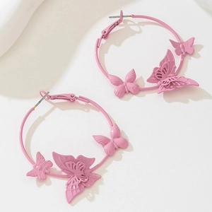 Detail of pink butterfly charms on large metal hoop earrings with elegant matte finish