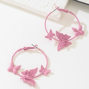 Detail of pink metal hoop earrings featuring three delicate 3D butterflies on a stone surface