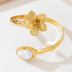 Detail of golden flower arm cuff with textured petals and a large white pearl accent