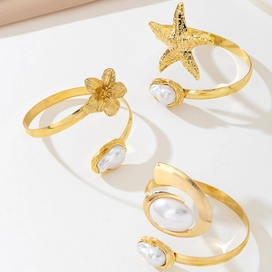 Detailed view of 3pcs gold ocean theme starfish and flower cuff bracelets with pearls