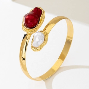 Gros plan du bracelet doré ouvert avec pierre rouge et perle baroque élégante