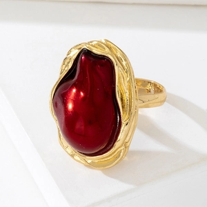 Statement gold ring featuring a large irregular red gemstone on minimalist white display