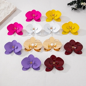 Colorful orchid flower stud earrings in various matte and gold finishes on a natural fabric