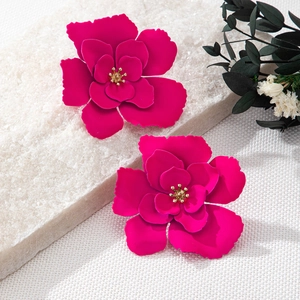 Gros plan de boucles d'oreilles fleurs 3D magenta avec centres dorés sur des pierres
