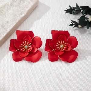 Gros plan détaillé d'une boucle d'oreille fleur rouge mat avec cœur doré et cristal