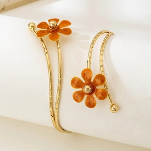 Dettaglio macro di un bracciale da braccio dorato a doppio strato con fiori in smalto arancio