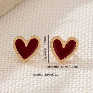 Elegant gold-edged red heart stud earrings for women shown on textured fabric background
