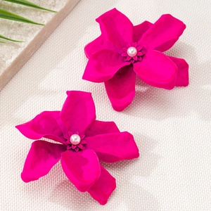 Detail of matte rose red flower earrings with white pearls on a neutral fabric background