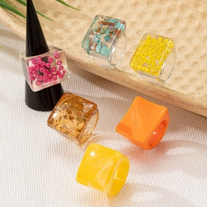 Transparent resin rings set with gold foil and colorful beads in irregular geometric shapes