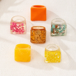 Detail of diverse resin rings featuring gold foil, beads, and clear geometric finishes