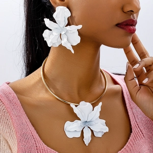 Gros plan d'un collier pendentif orchidée blanc mat et de grandes boucles d'oreilles