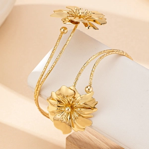 Golden floral open cuff armlet with textured metal band and layered flower design