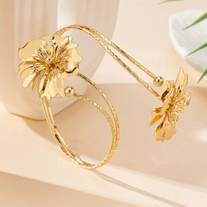 Elegant gold metal floral arm cuff with textured blooming flowers and layered open band