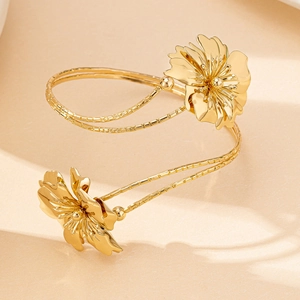 Detail of a gold floral upper arm cuff with 3D textured petals on a matte background
