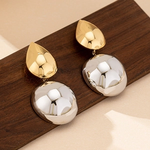 Minimalist bicolor drop earrings with gold and silver oval shapes on wood background