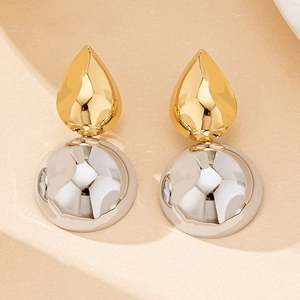 Macro detail of geometric drop earrings with polished gold and silver metallic finish