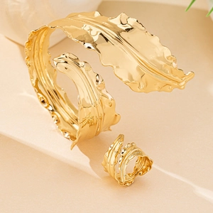 Detailed view of leaf pattern gold open bracelet and ring set with hammered texture
