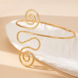Modieuze gouden gedraaide open armband met een elegante gehamerde metalen afwerking