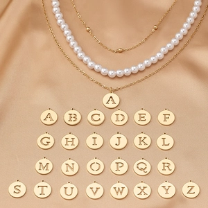 Detail of layered gold chain necklace with white pearls and 26 alphabet pendants