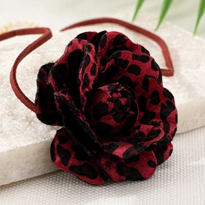 Makro-Detail eines handgefertigten Chokers mit Leopardenmuster-Rose und rotem Veloursband