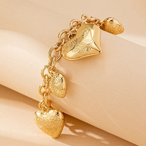 Bracciale dorato con ciondoli a cuore con incisione LOVE e rose a rilievo su sfondo neutro