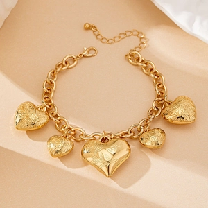 Dettaglio del bracciale dorato con ciondoli a cuore e motivo di rose in rilievo