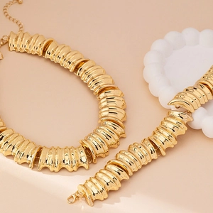 Nahaufnahme der gerippten Textur auf poliertem Goldschmuck-Set mit Halskette und Armband