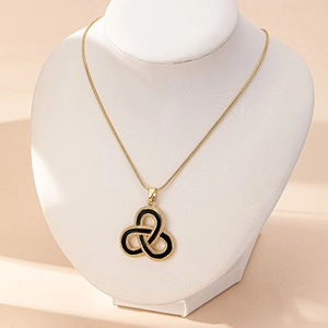 Dettaglio della collana a catena serpente dorata con ciondolo a nodo celtico nero e oro su busto