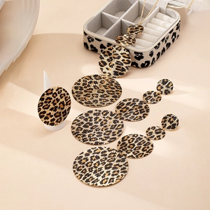 Dettaglio del set di gioielli leopardati con collana, orecchini e anello su sfondo beige