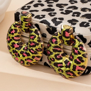 Detail of C-shaped leopard print earrings with vibrant neon green and gold patterns