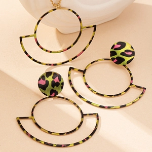 Close-up of geometric gold jewelry set with neon green leopard print pattern texture