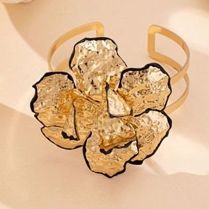 Dettaglio macro del bracciale a polsino con fiori dorati, petali martellati e bordi neri
