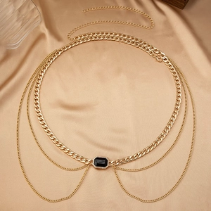 Detail of layered gold waist chain featuring a black emerald-cut gem with diamond halo
