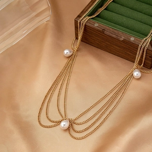Bohemian gold layered necklace featuring elegant white pearl pendants on satin background