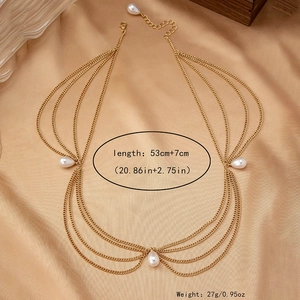 Detail of bohemian gold body chain with white teardrop pearls over gold silk background