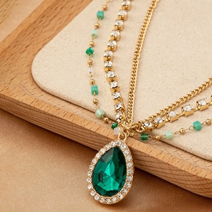 Collier bohème multicouche avec pendentif émeraude, perles dorées et accessoire gland