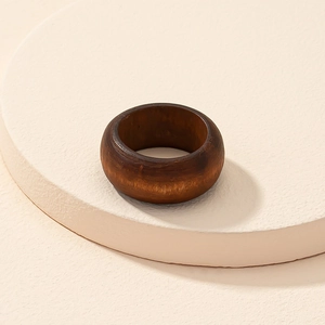 Minimalist dark brown wooden ring with natural grain texture on a neutral display