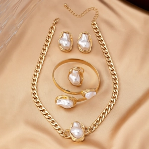 Détail de parure de bijoux perles baroques et texture lave sur soie couleur champagne