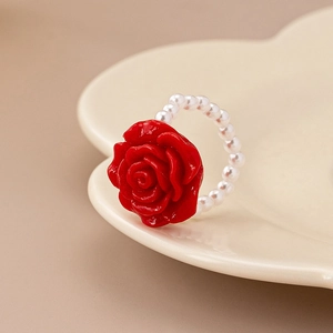 Elegant red rose pearl chain ring displayed on a heart-shaped ceramic jewelry tray