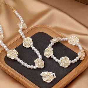 Detail eines eleganten Perlenschmuck-Sets mit weißen Rosen und goldenem Rand