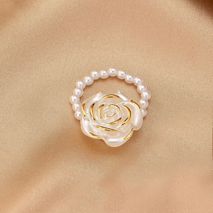 Close-up of elegant rose pearl ring with gold-edged petals on champagne satin cloth