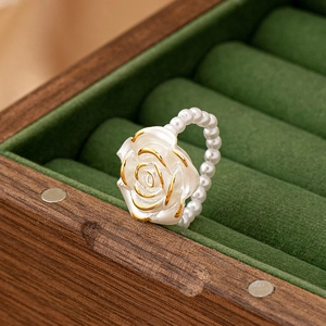 Detail of vintage rose ring with matte petals and white pearl chain band on velvet
