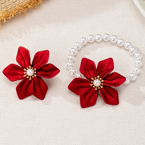 Elegant floral hair accessory set with red flowers and white pearls on beige fabric