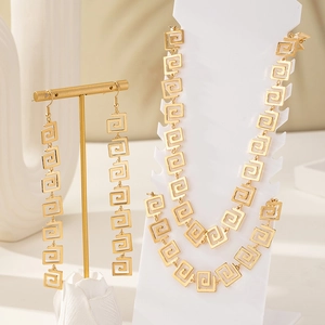 Detail of gold jewelry set with Greek key patterns on necklace and drop earrings