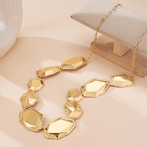 Chic golden belt chain with irregular geometric prisms on a minimalist display stand
