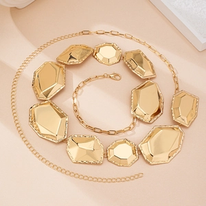 Gold-tone geometric faceted metal waist chain belt with lobster clasp on pink background
