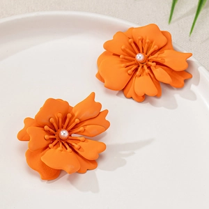 Detail von matten orangefarbenen Blumenohrringen mit Schichtblüten und Perlenmitte