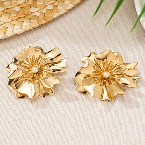 Goldene Blumenohrringe mit geschichteten Blütenblättern und Perle auf Texturhintergrund