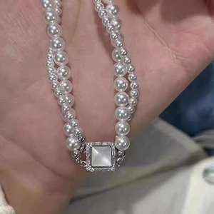 Detail of a double-strand pearl bracelet with square shell pendant and micro inlay
